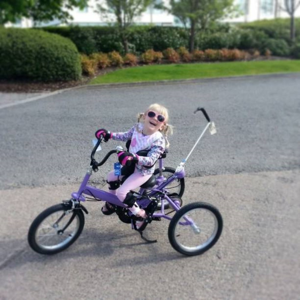 Mini gripping aid for children. girl using mini to hold onto trike. Suitable for reduced hand function: tetra, quad, cerebral palsy, SCI, spinal cord injury, stroke and more.