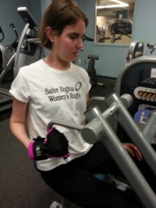 Rebecca works out in the gym with her pink general purpose gripping aid