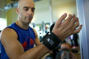 Looped aid on Rob's wrist in gym. Adaptive gym equipment. Suitable for reduced hand function: tetra, quad, cerebral palsy, SCI, spinal cord injury, stroke and more.