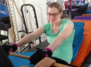 Rachael Watson in gym with General Purpose aid. Adaptive gym equipment. Suitable for reduced hand function: tetra, quad, cerebral palsy, SCI, spinal cord injury, limb difference, stroke and more.