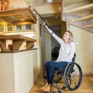 Reacher/ grabber for quads - woman reaching high shelf. Suitable for reduced hand function: tetra, quad, cerebral palsy, SCI, spinal cord injury, stroke and more.