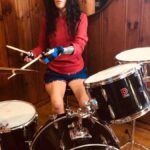 lady playing the drums using the small item gripping aid to hold her drumsticks