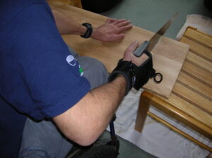 Rob using the General purpose aid to hold a saw while sawing a piece of wood.