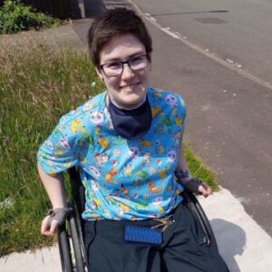 Tess sitting her wheelchair outside