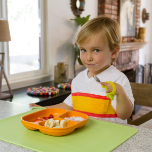 A child with a limb difference using the yellow EazyHold to hold cutlery