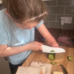 Isabelle, who has an upper limb limb difference, uses the food preparation board to chop cucumber