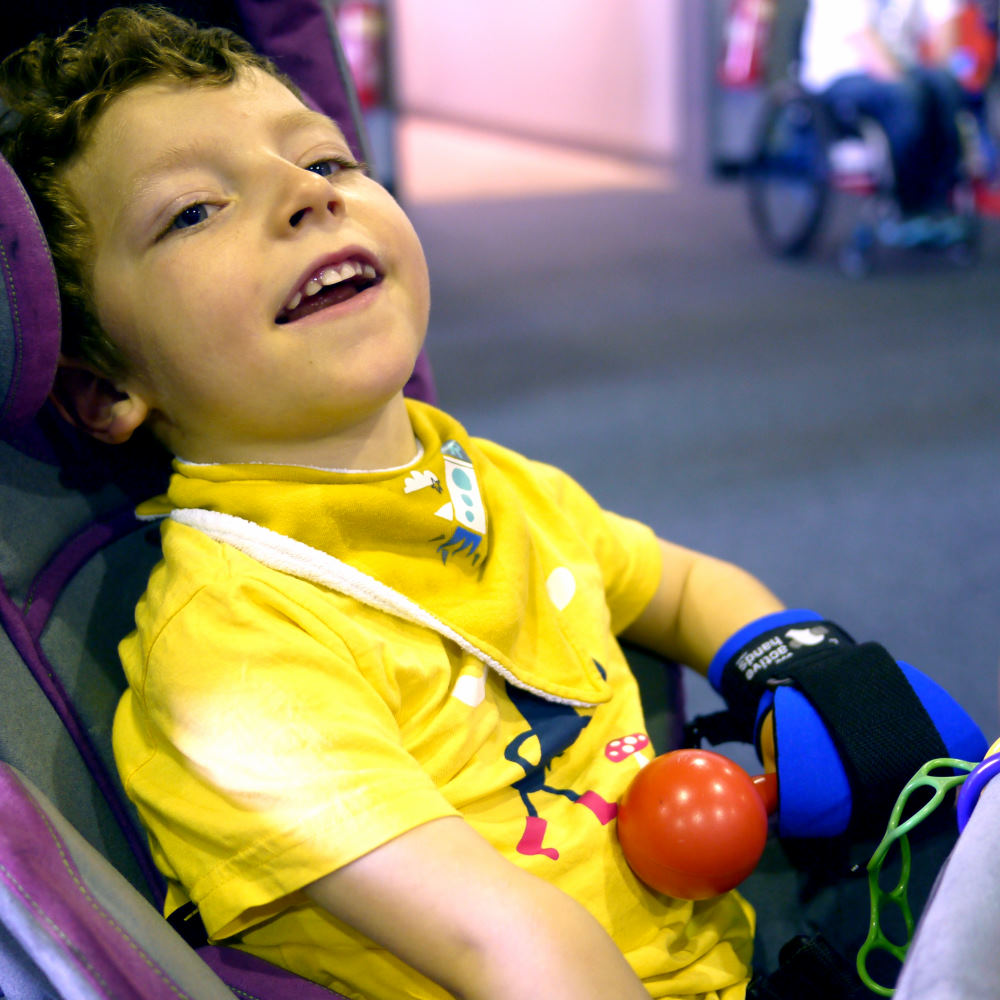 Euan using blue mini gripping aid to hold rattle