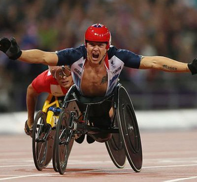 David Wear celebrating in his racing chair with his arms open wide and shouting