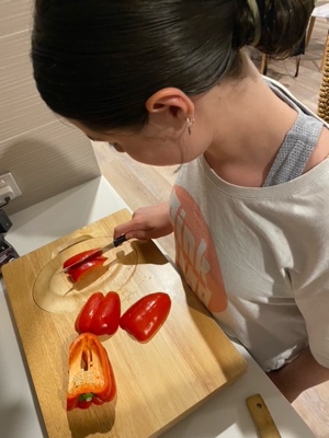 a young girl uses the food prep board to chop up a pepper. The pepper is held on the spike so only one hand is needed