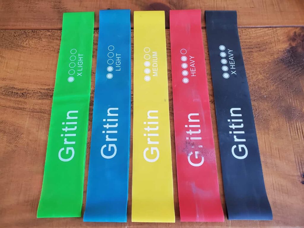 a set of different strength therabands in green, blue, yellow, red and black