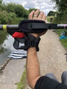 picture shows an arm holding a kayak paddle next to a canal, using our kayak adaptations to grip it.
