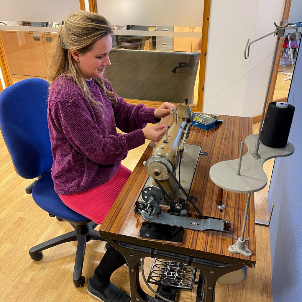 Sarah sat at the sewing machine in the Active Hands office