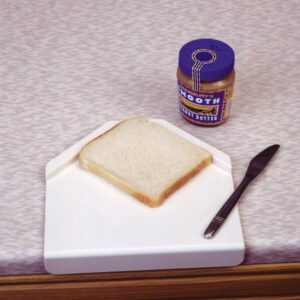 sandwich prep board with bread, a knife and a jar of peanut butter