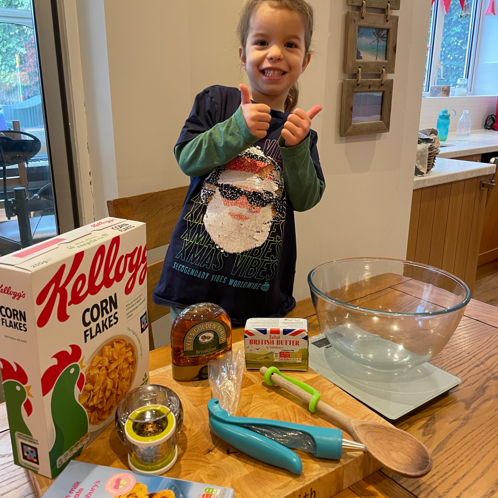 Girl stood behind a table with the ingredients and tools to make a Christmas Wreath cake