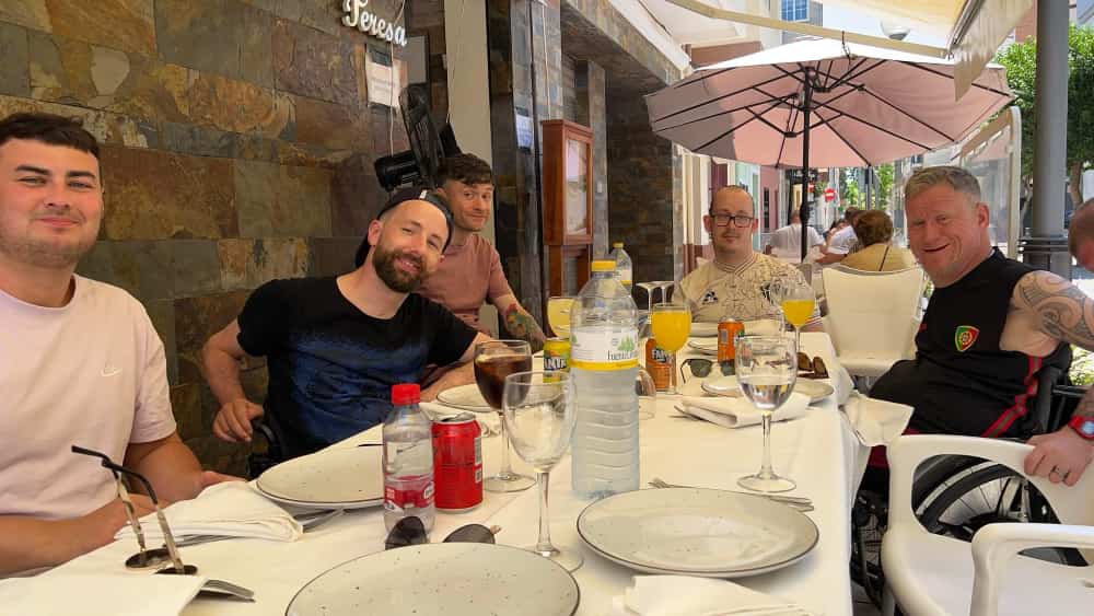 Gareth is wearing a black cap backwards while out at a meal with friends