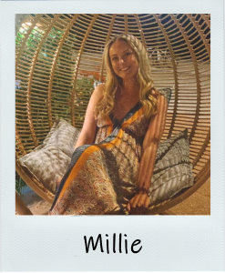 A picture of Millie sitting in a swing chair, in a long summer dress, looking relaxed