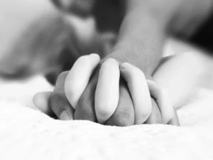 black and white image of two hands holding each other with fingers entwined.