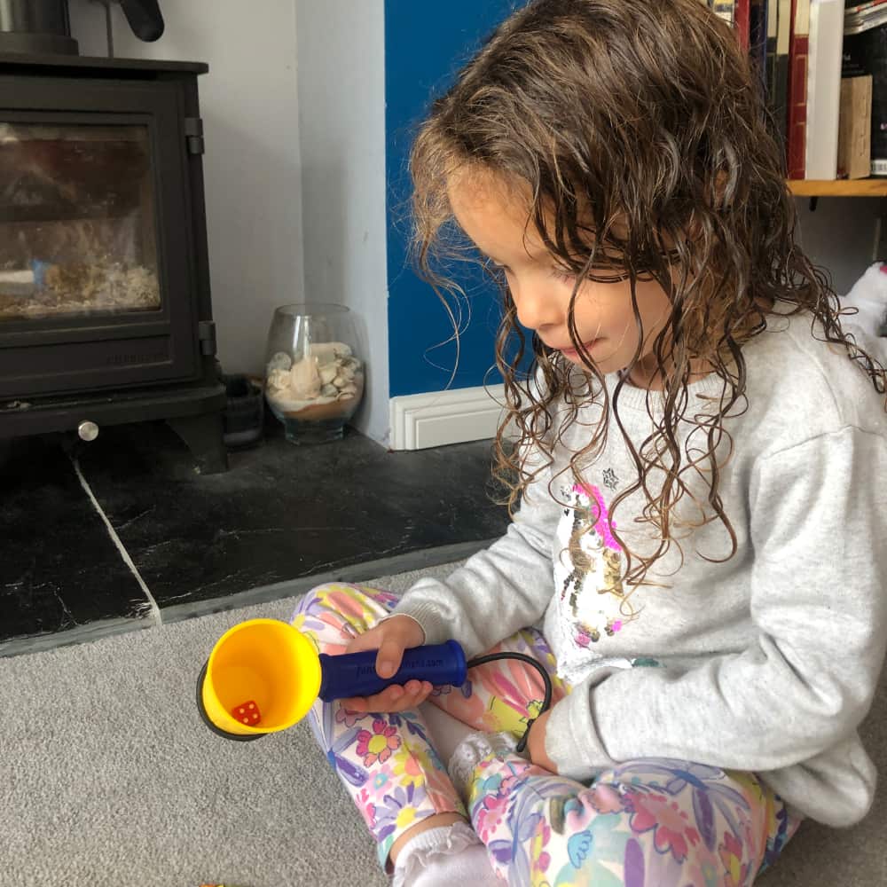 A child using the functional hand to hold a cup containing a dice in order to play a game