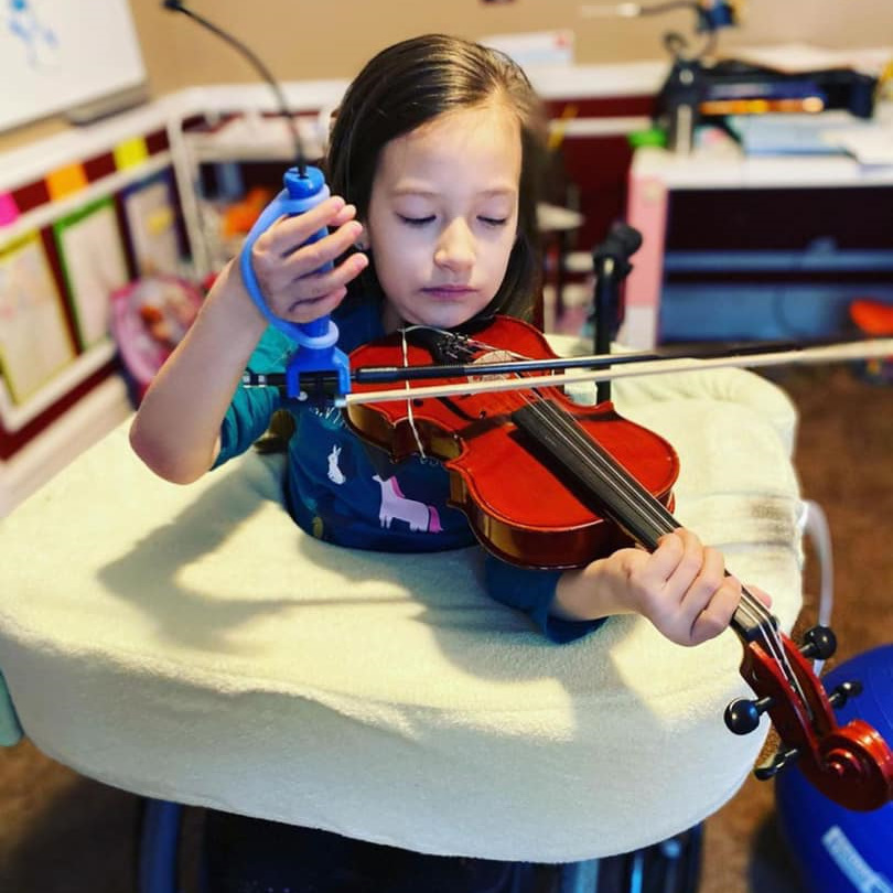 Girl using a function hand attached to a bow to play the violin