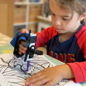 A child uses the mini small item aid with a felt tip to colour in a picture