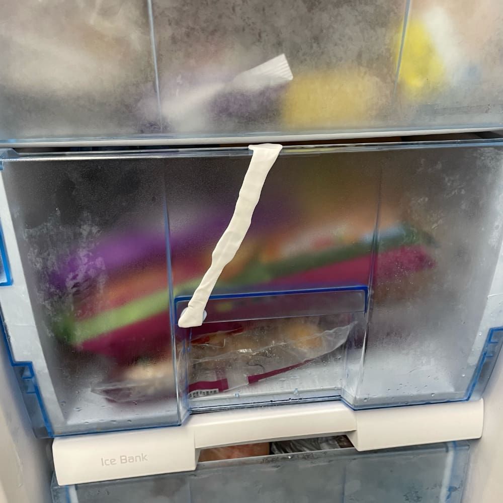 A white FixIt has been used to mend a cracked freezer drawer.