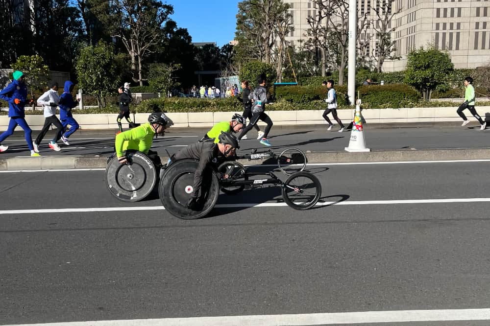 Rob mid-race in his racing wheelchair overtaking two other wheelchair racers