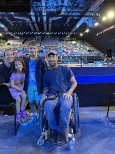 Rob, a wheelchair user, and his family sit in the stadium for the Paralympics wheelchair rugby.