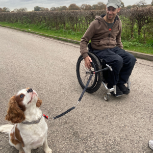 Rob using the wheelchair dog lead with a cute King Charles Spaniel sitting