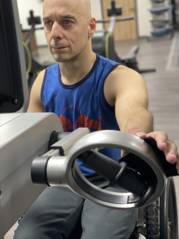 image shows rob using a hand cycle, holding the handle using a Hook Aid