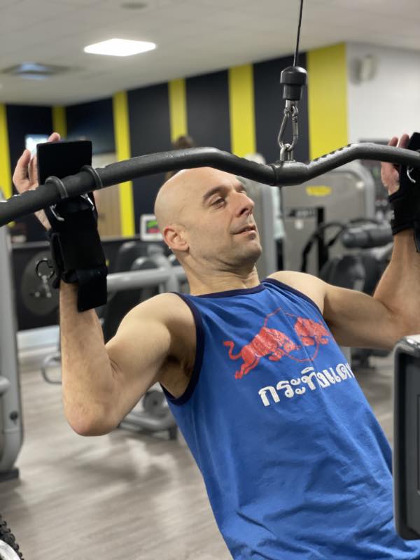 Rob pulls down the handle of a lat pull down machine, holding the handle using two hook aids