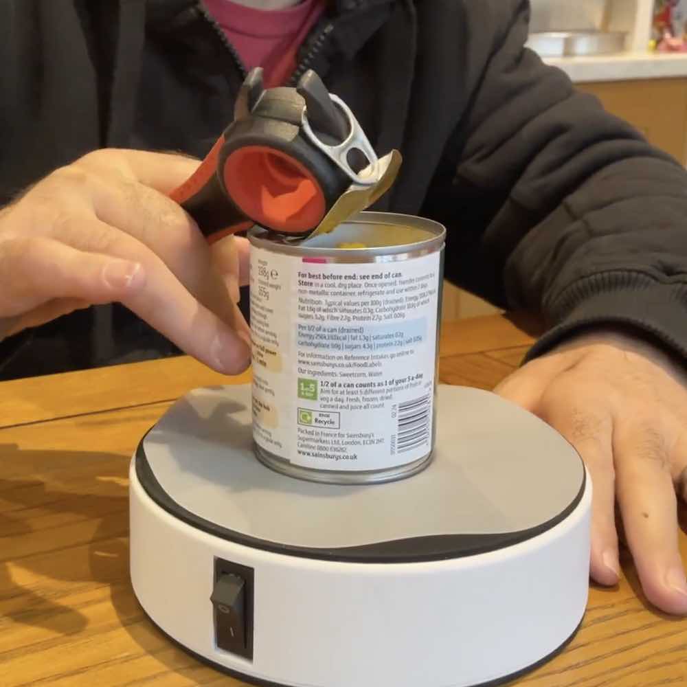 image shows a ring pull tin can being opened one-handed thanks to the Hold Fast Vacuum Platform.